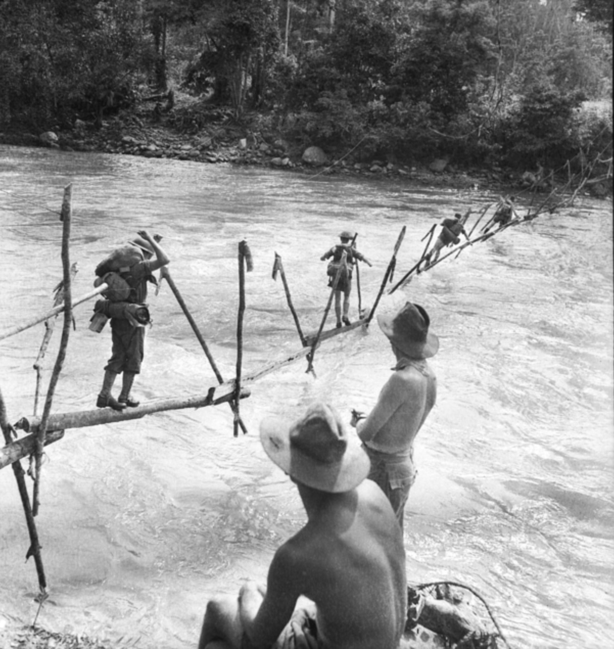 On the road to Buna, Australian troops cross a stream on an improvised bridge. 